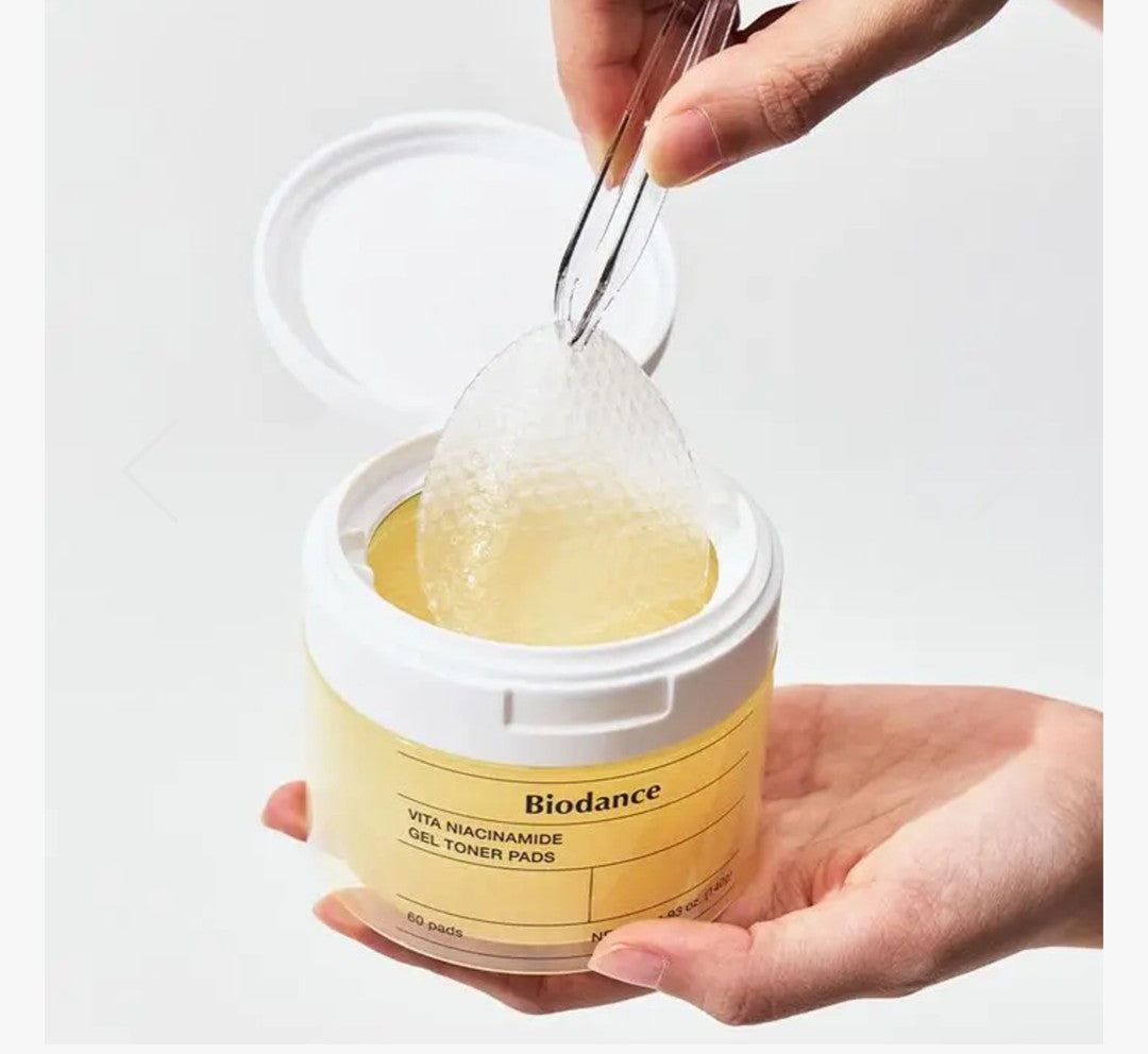 Person using a spoon to scoop out Biodance gel-toner pads from a container.