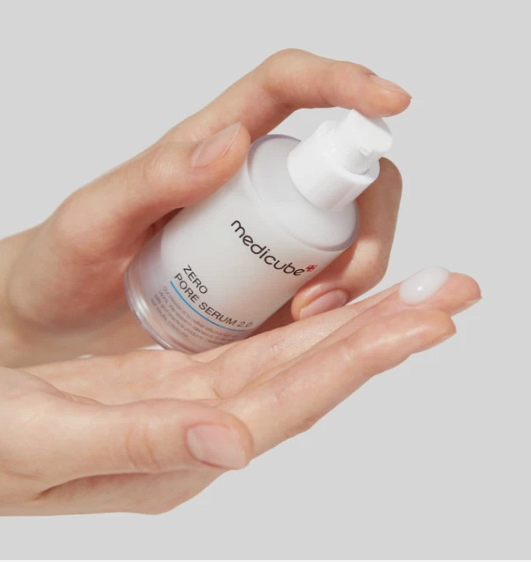 Hand holding a Medicube serum bottle against a light gray background