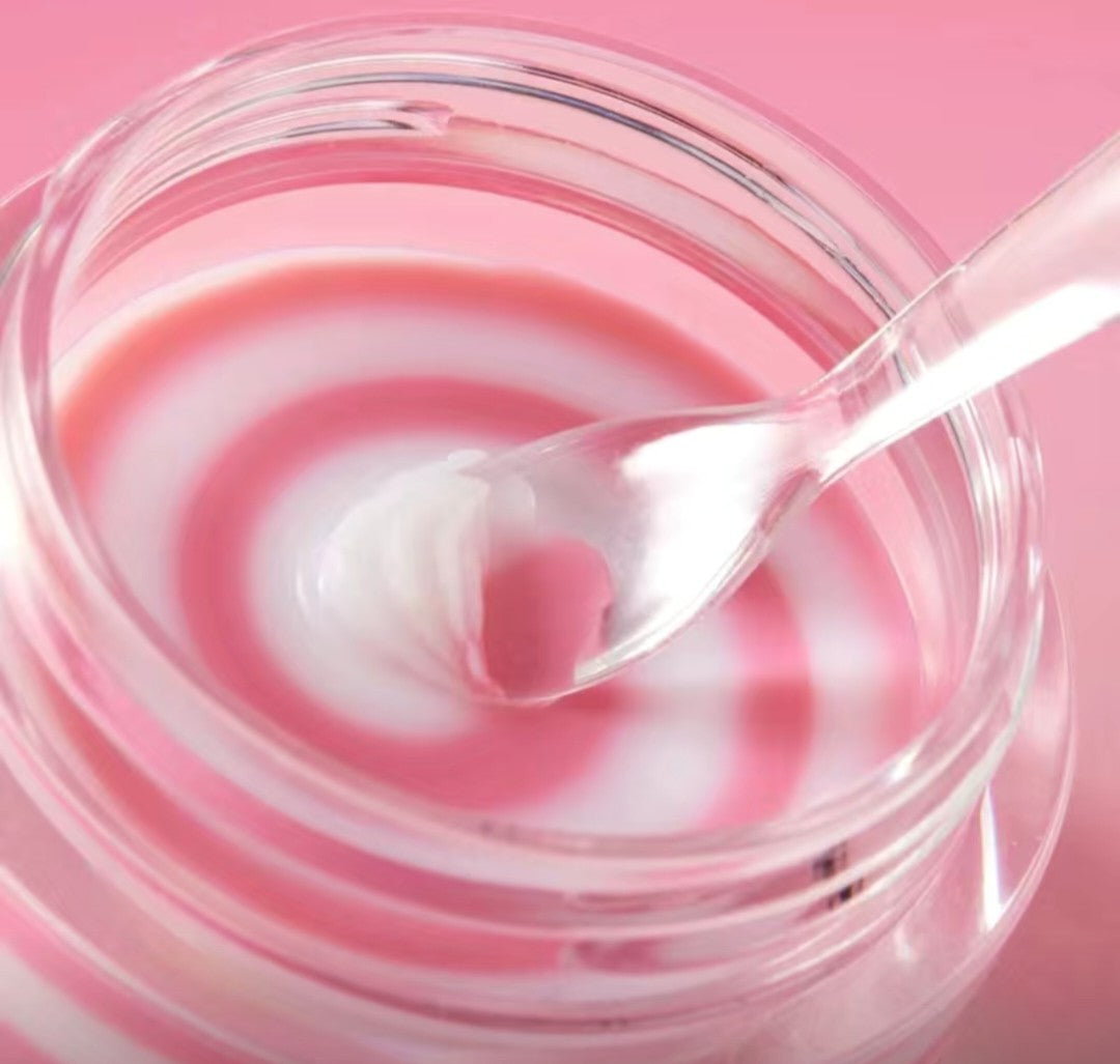 Pink and white swirl dessert in a clear bowl with a spoon on a pink background