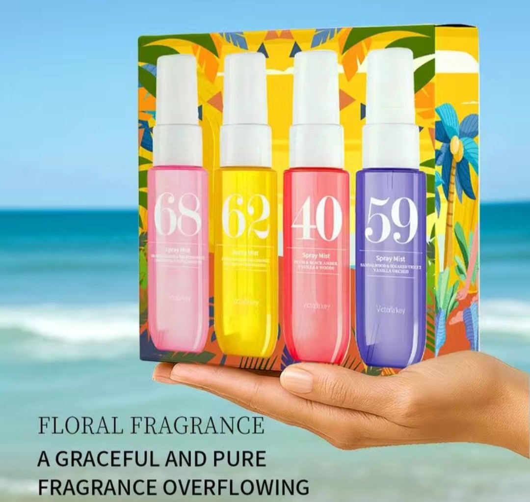 Set of four floral fragrance spray bottles with colorful packaging against a beach background