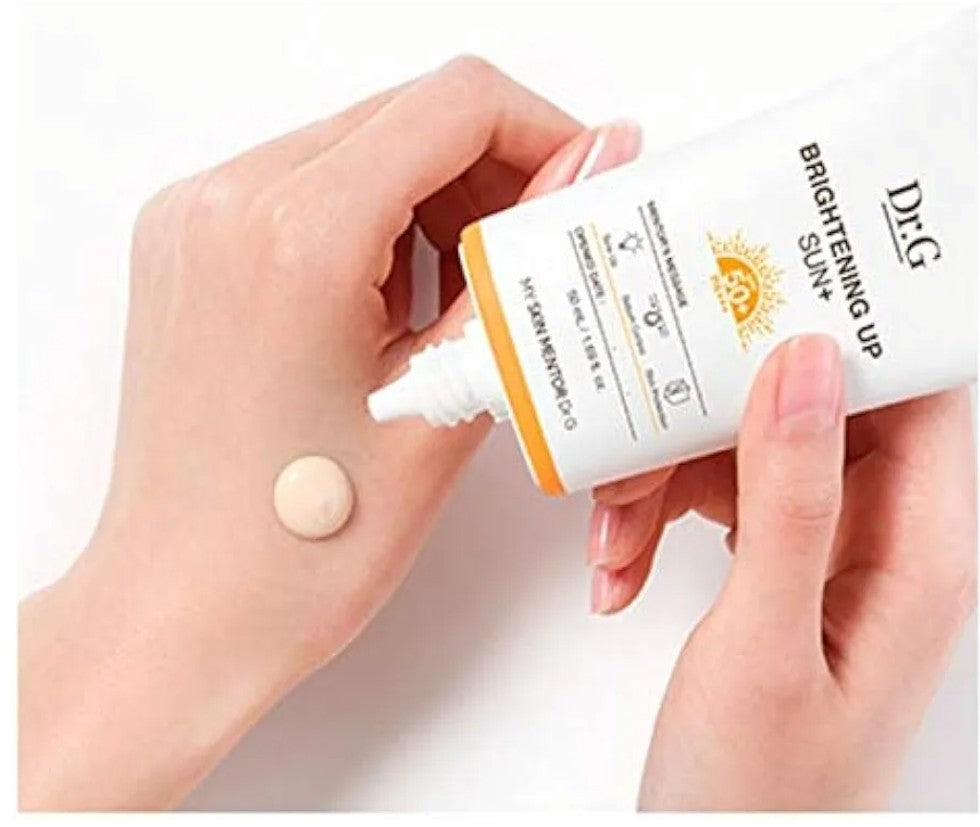 Hand applying sunscreen cream to a palm with a white background