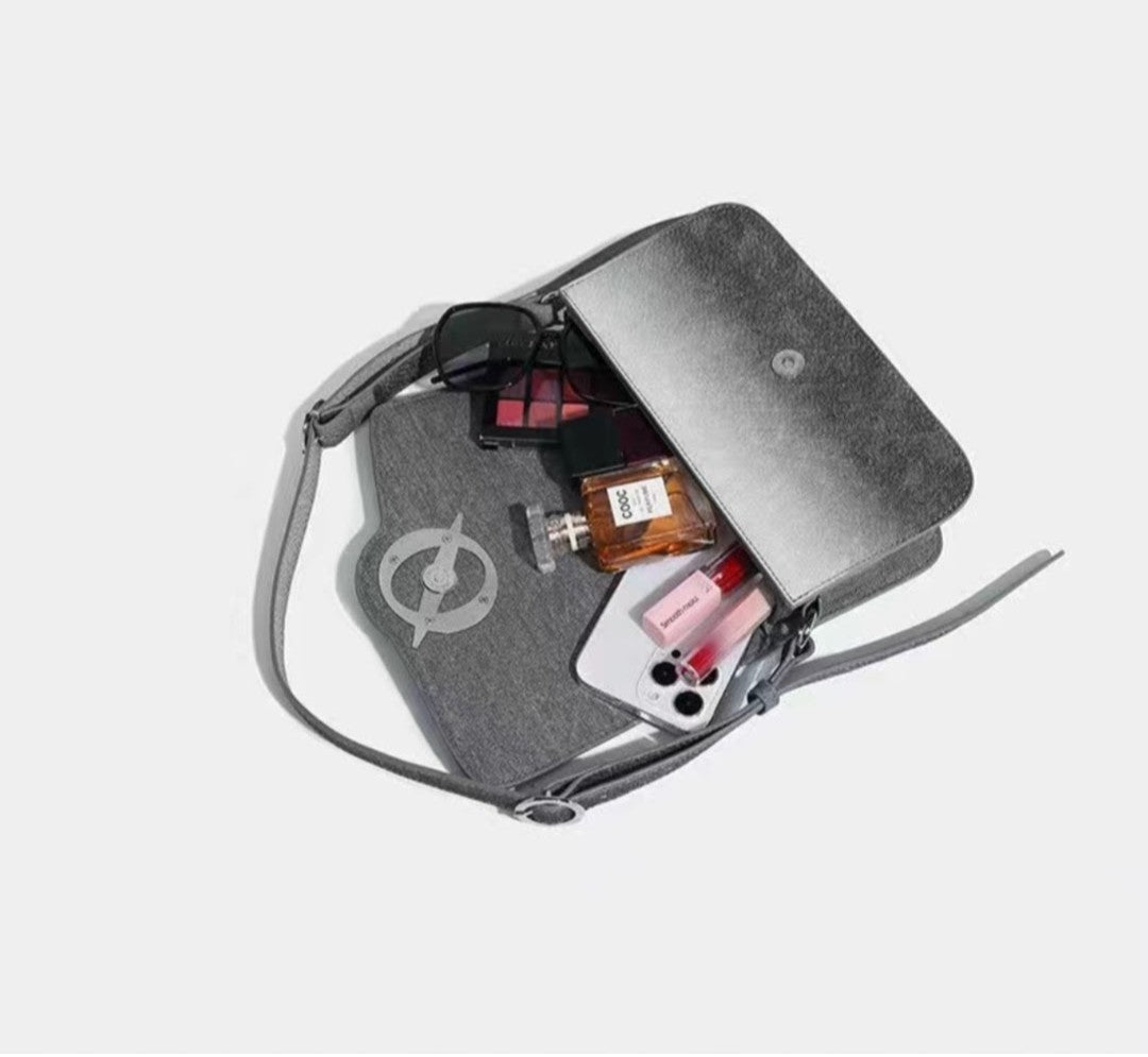 Gray crossbody bag with items inside on a white background