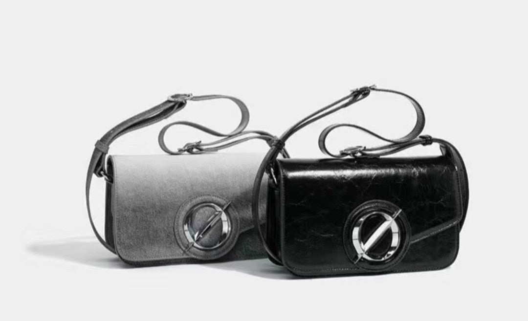 Two black handbags with metallic accents on a light gray background