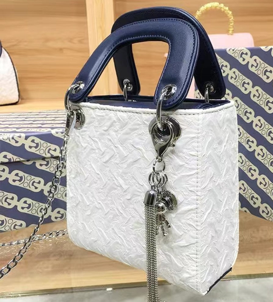 White textured handbag with blue handle on a wooden surface