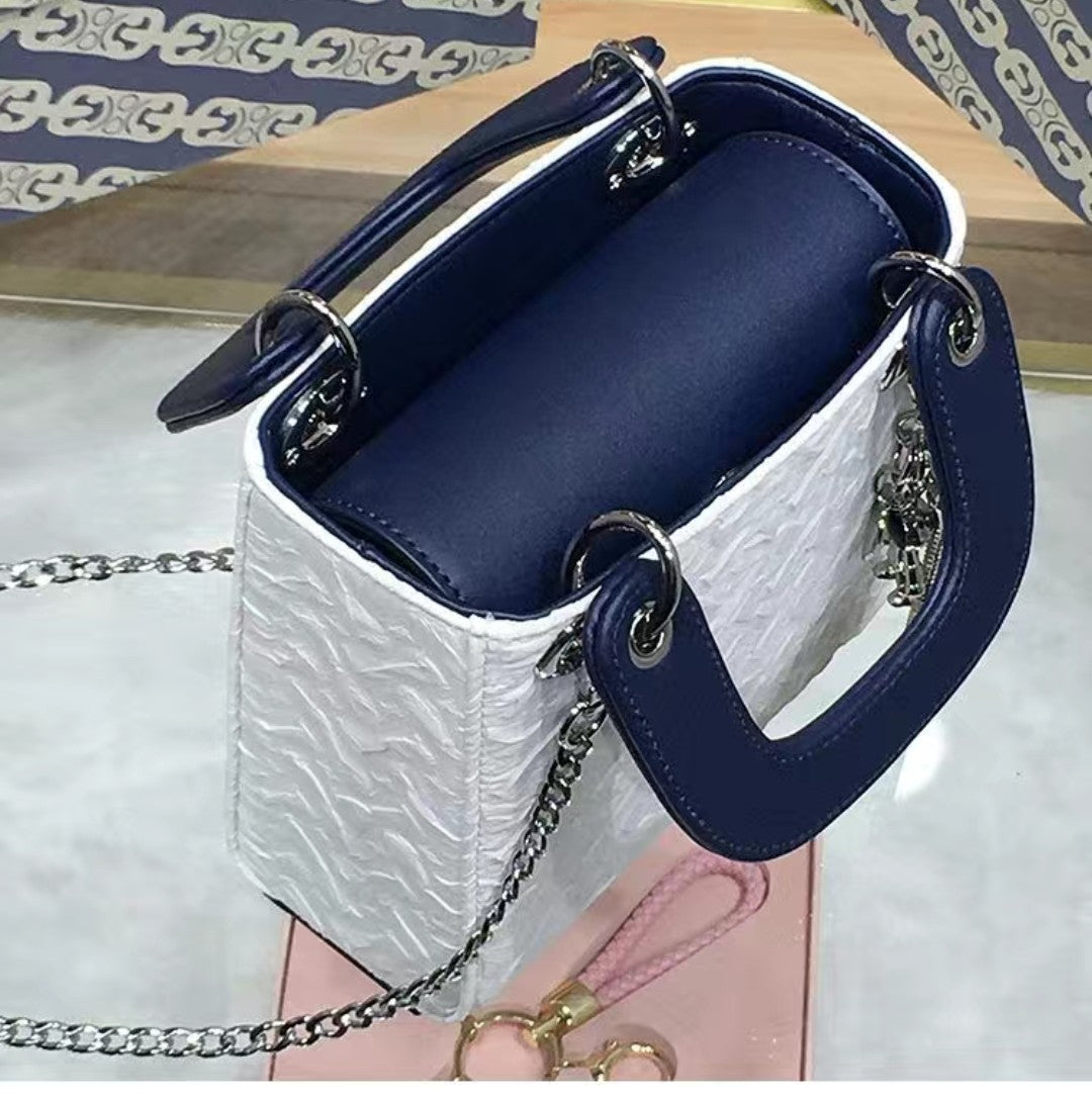 Side angle of GlowBags mini handbag showing embossed PU leather and navy handle