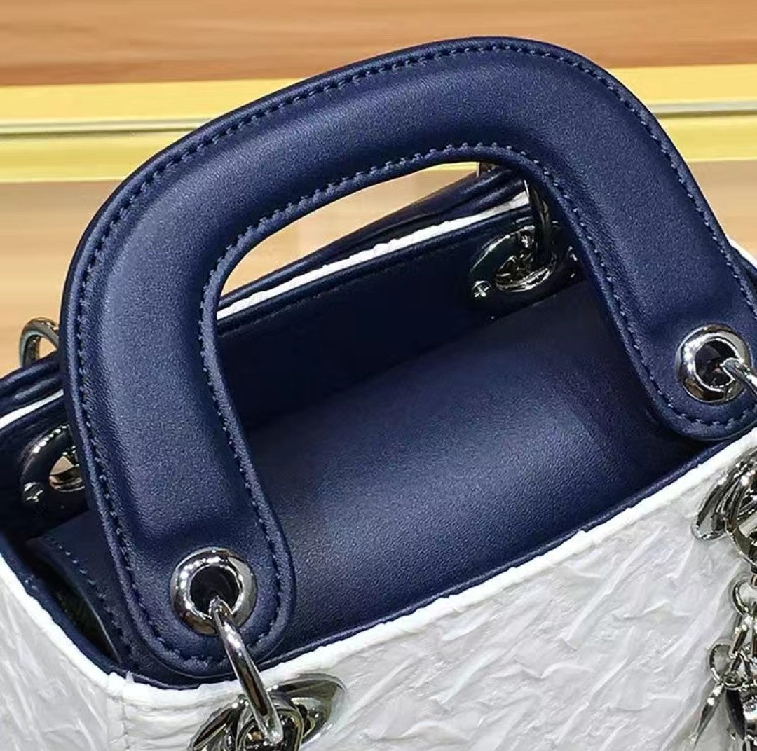 Close-up of a blue handbag handle with metallic hardware on a wooden surface