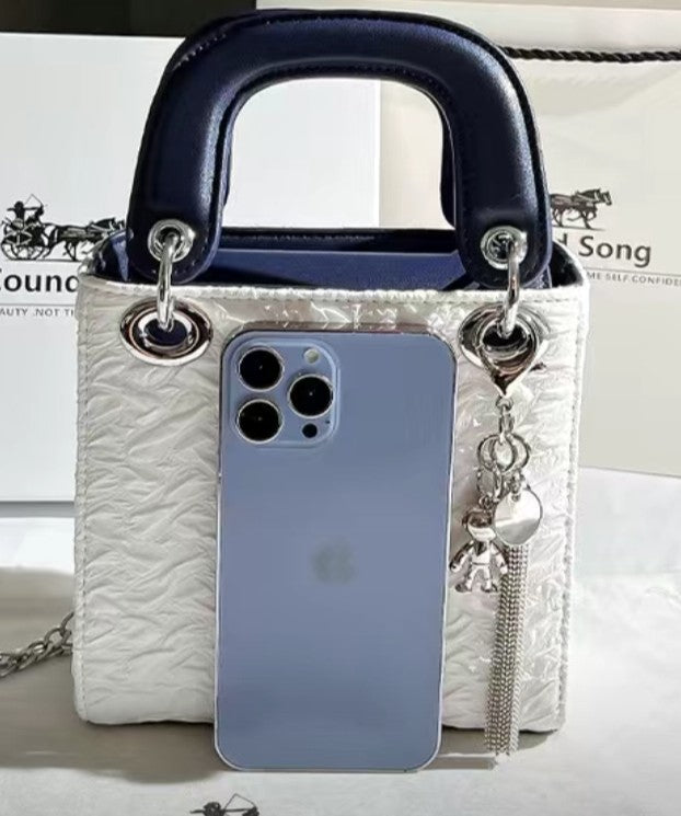 Phone case with silver accents and charms on a white surface