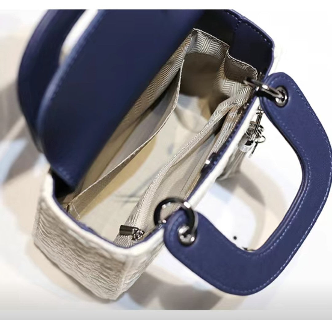 Close-up of a blue handbag with a silver interior on a white background