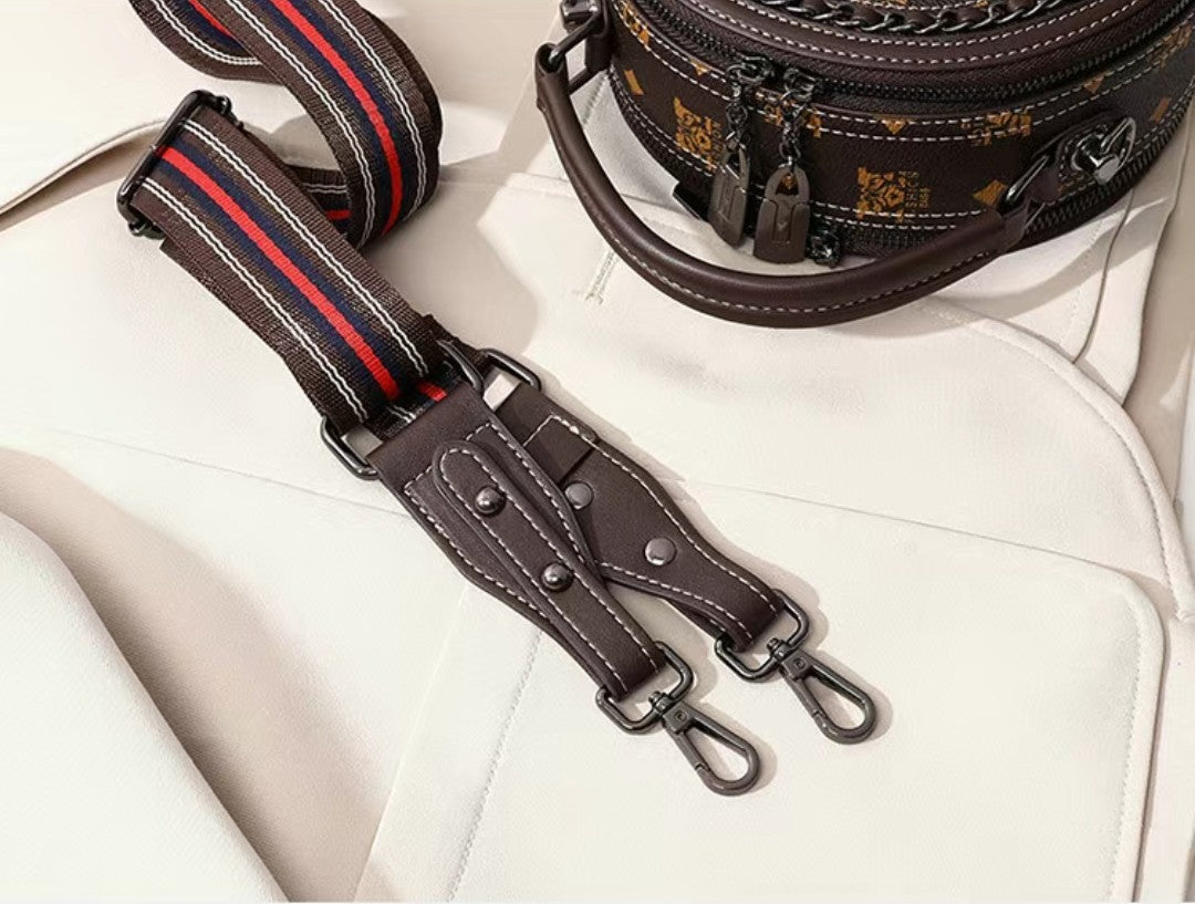 Brown leather bag with a strap featuring red and blue stripes on a white background