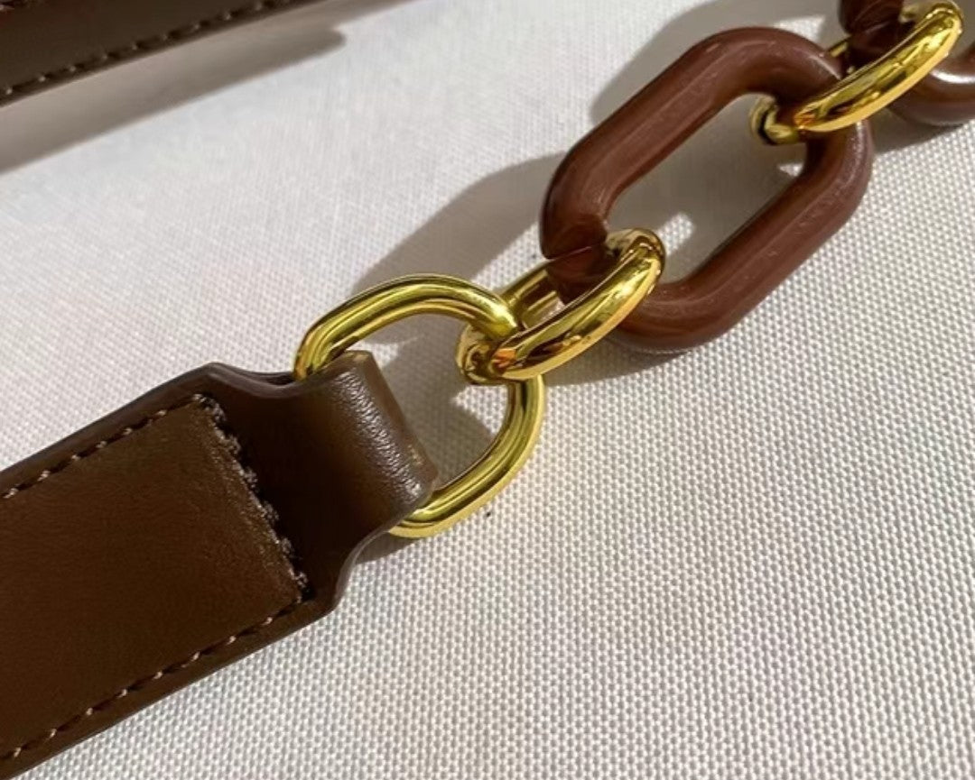 Brown leather strap with gold chain links on a white background