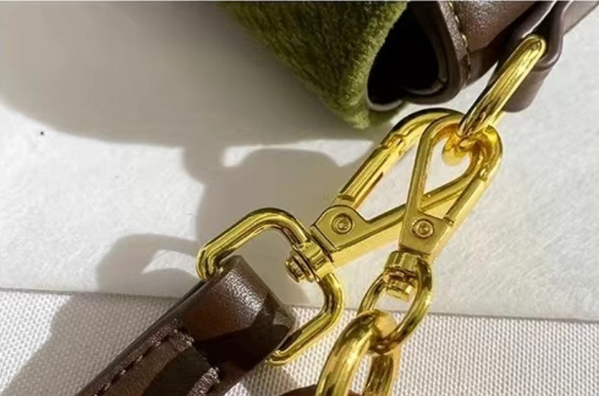 Close-up of green embossed shoulder bag with gold chain clasp and brown leather strap