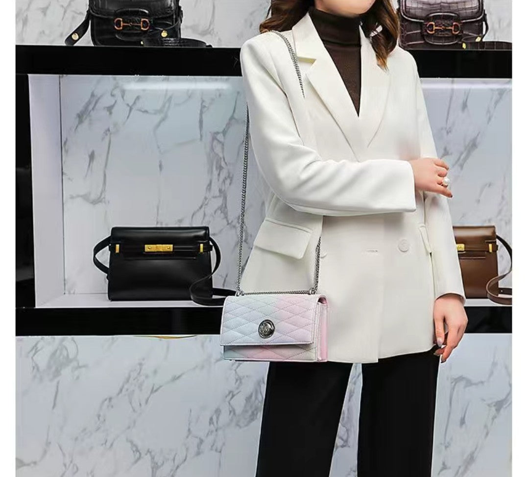 Woman in a white blazer holding a pastel quilted handbag with a marble background.