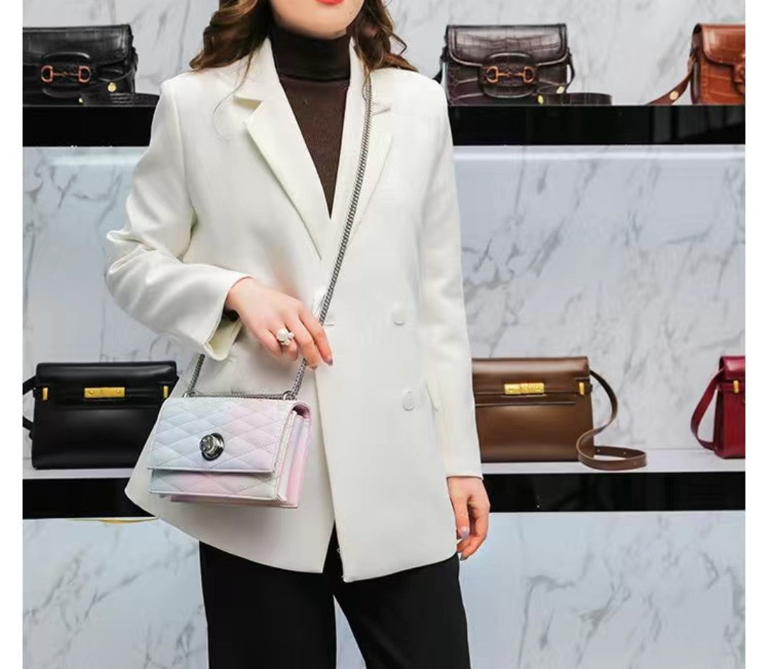 Person wearing a white coat holding a handbag with a marble wall and bags in the background