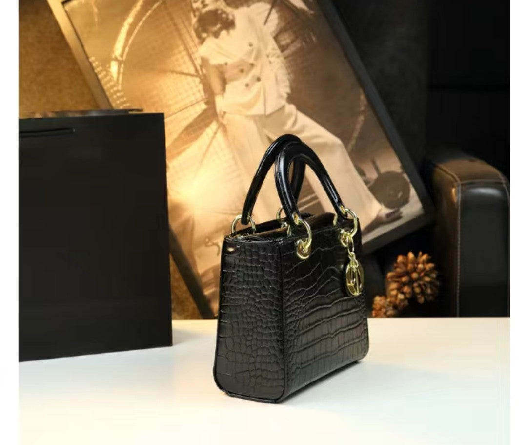 Black handbag with gold accents on a white surface, with a blurred background