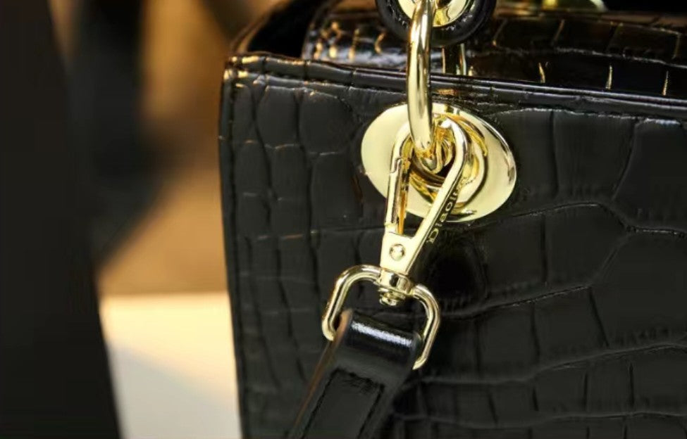 Black textured handbag with a gold chain and clasp