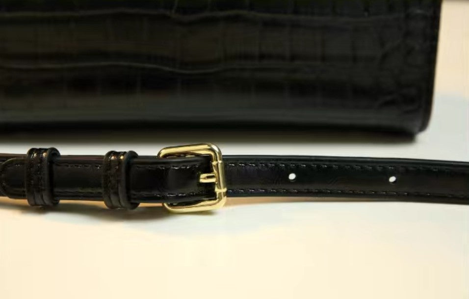 Black leather belt with a gold buckle on a light background