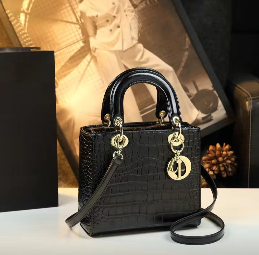 Black handbag with gold accents on a white surface, blurred background