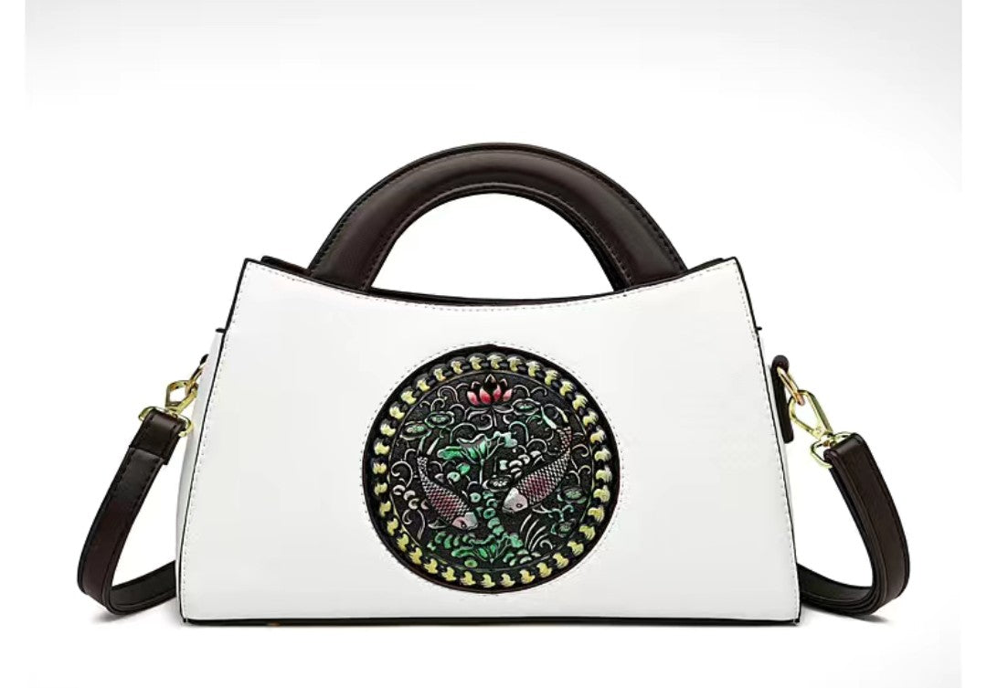 White handbag with decorative circular emblem featuring birds on a white background