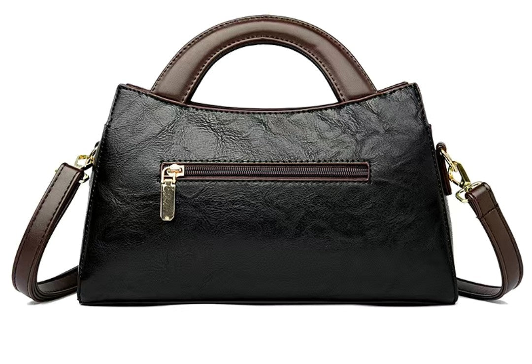 Black handbag with brown accents on a white background