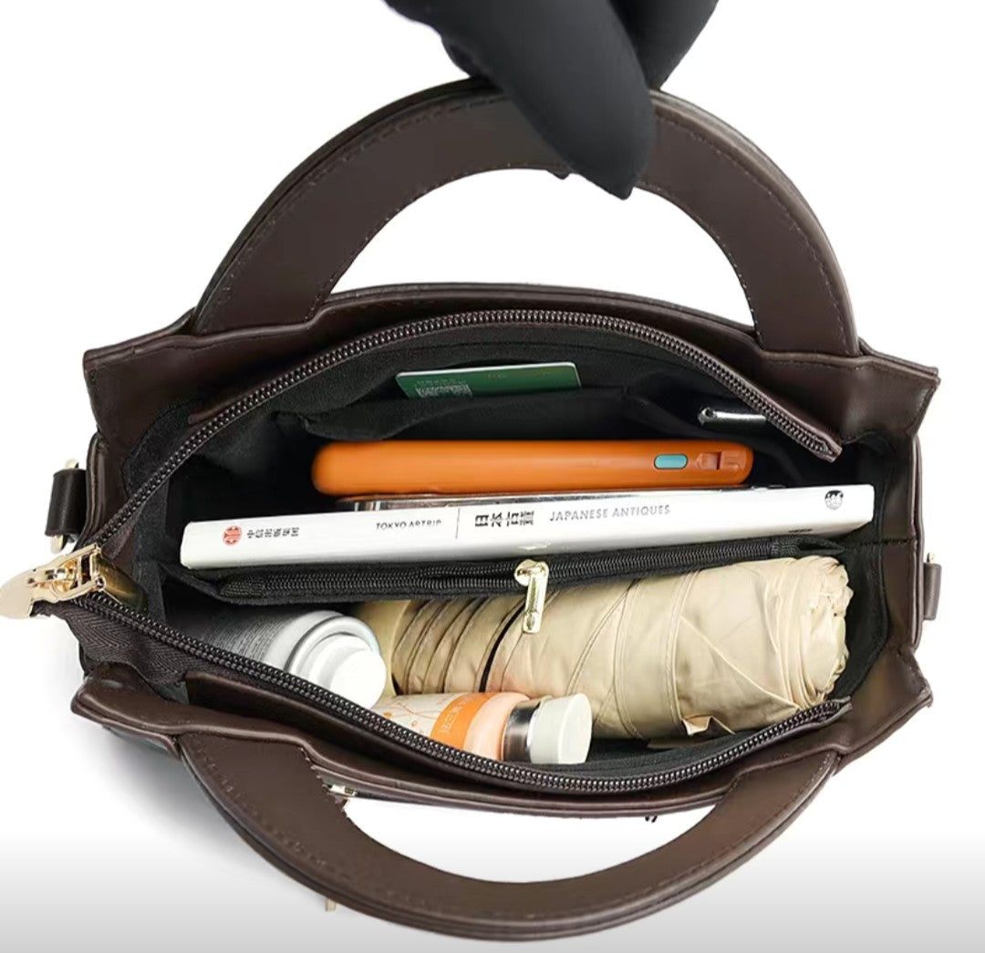 Brown handbag with items like a phone, books, and an umbrella inside on a white background