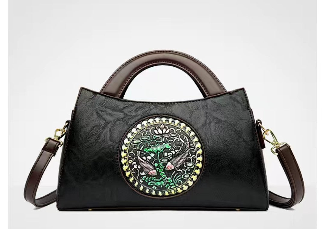 Black handbag with decorative emblem on a white background