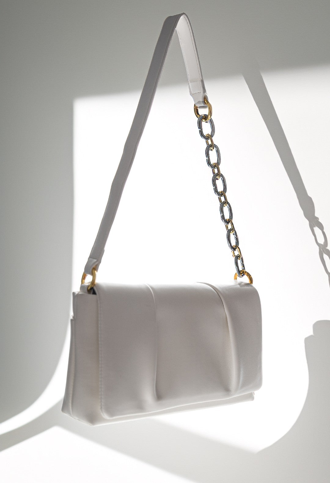 White handbag with a gold chain strap on a white background