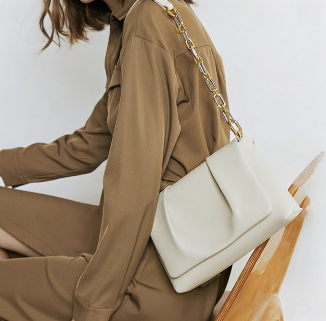Person wearing a brown outfit with a white handbag on a white background