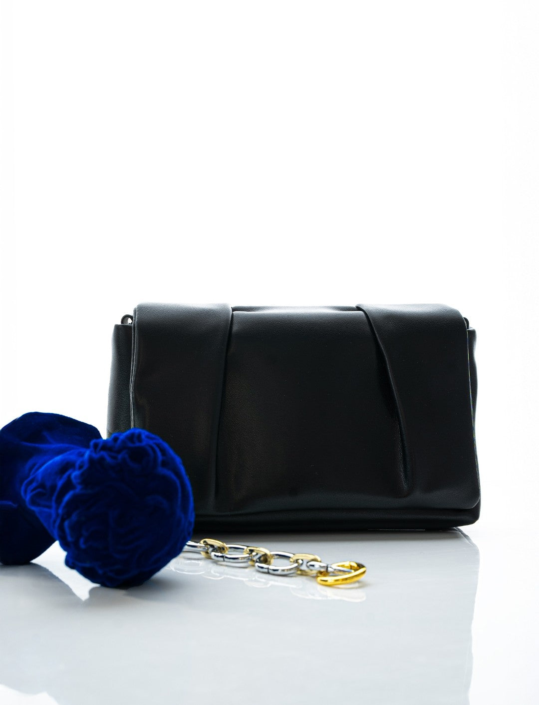 Black clutch bag with gold chain and blue flowers on a white background