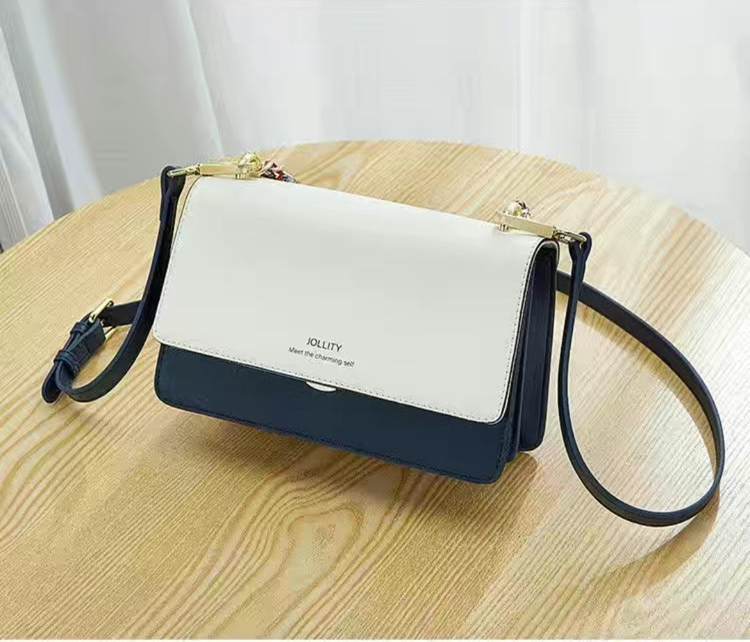 Two-tone handbag with white top section and navy bottom section on a wooden table.
