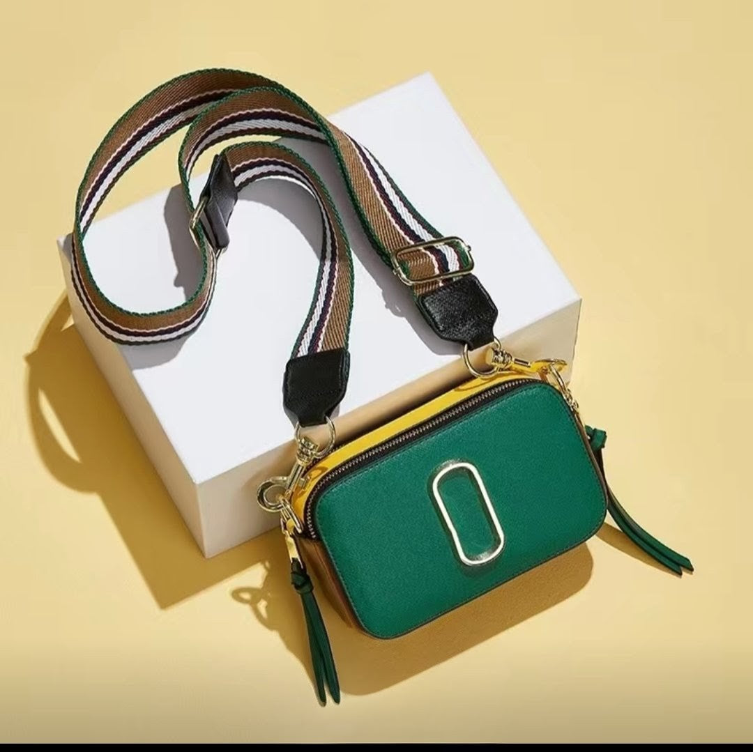 Green handbag with a striped strap on a yellow background