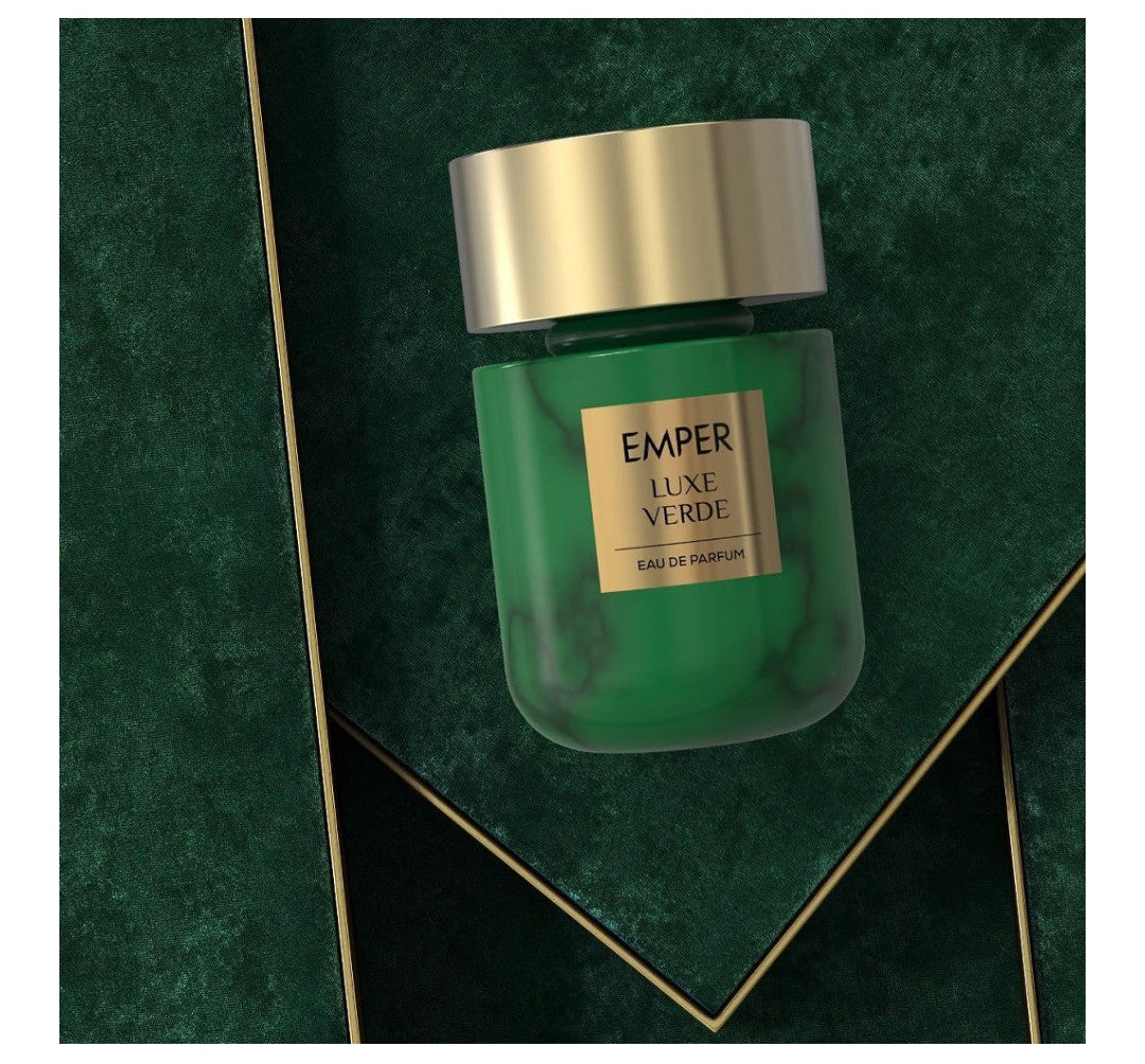 Green perfume bottle with gold cap on a green textured background