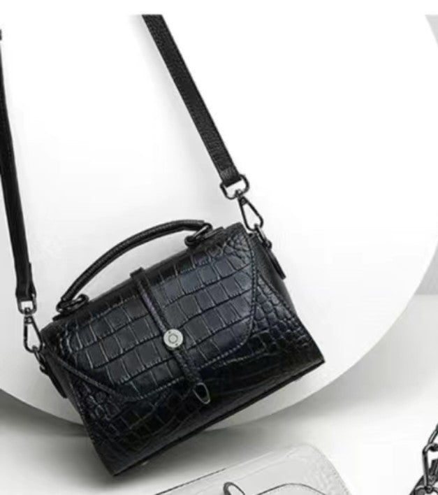 Black crocodile-patterned handbag on a white background