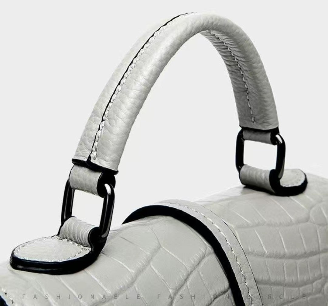 Close-up of a white textured handbag with a handle on a white background