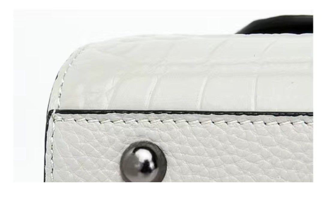 Close-up of a white textured handbag with a metallic button on a white background
