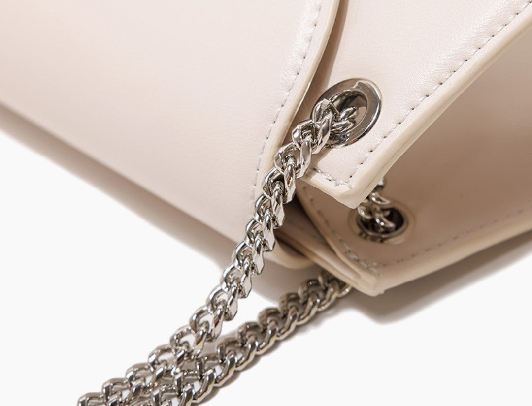Close-up of a white handbag with a silver chain strap on a white background
