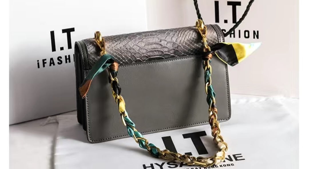 Back view of grey crocodile-embossed shoulder bag with gold chain and silk scarf detail