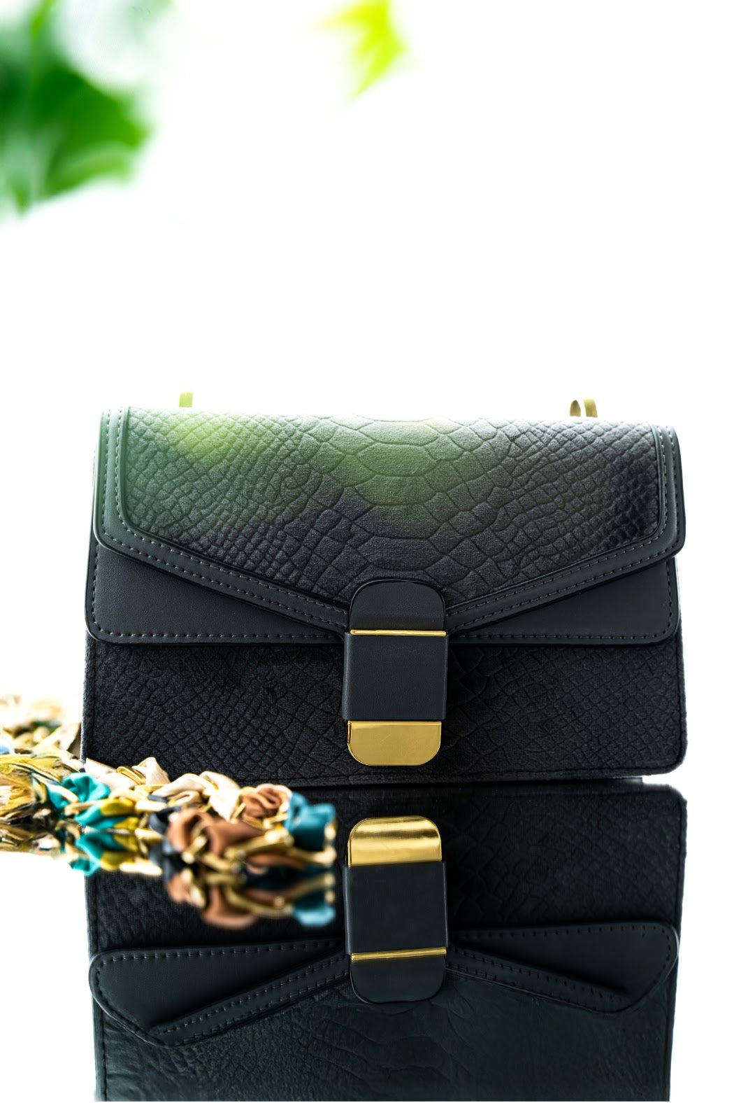 Black and green handbag with gold accents on a white background