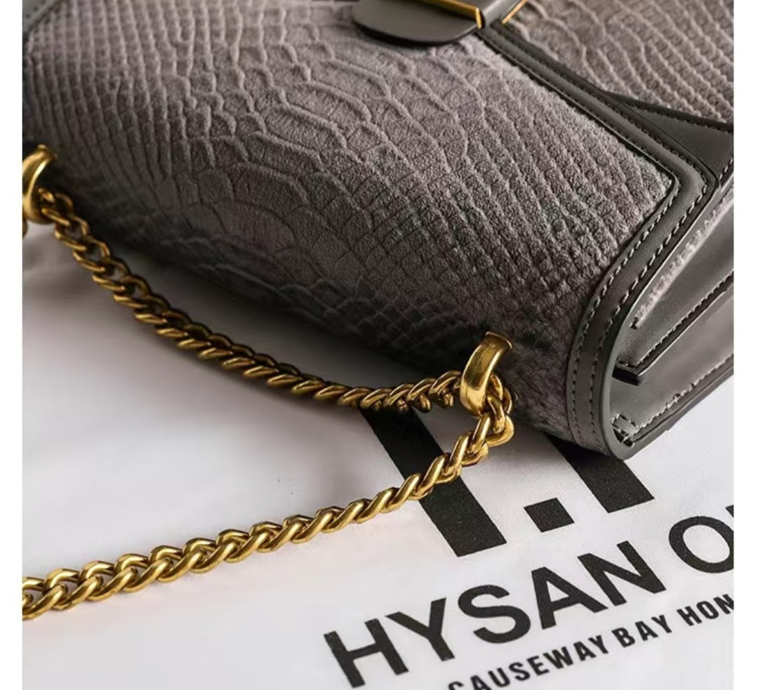 Gray textured handbag with a gold chain on a Hysan One Causeway Bay Hong Kong background