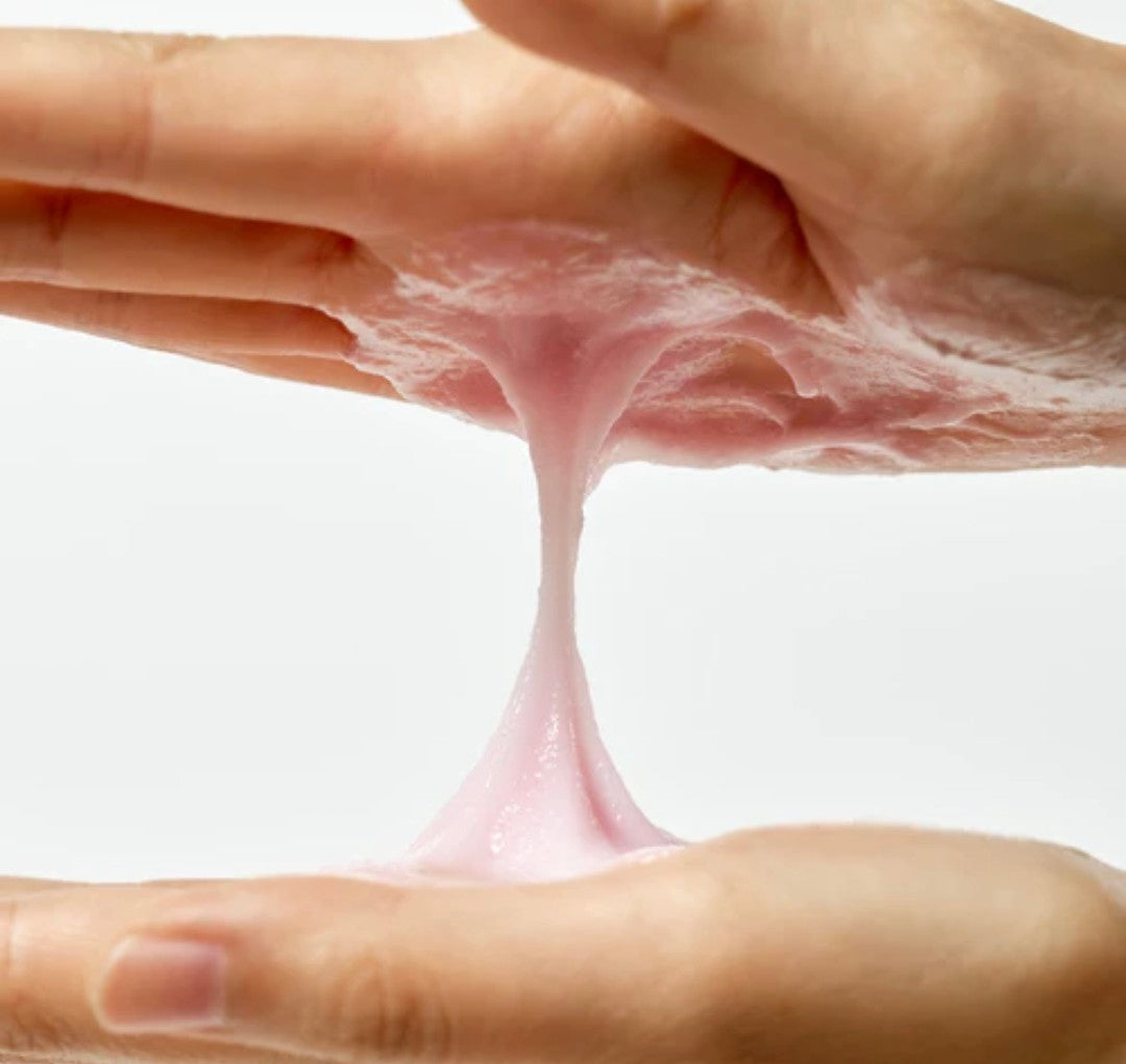 Pink slime stretching between two hands on a white background