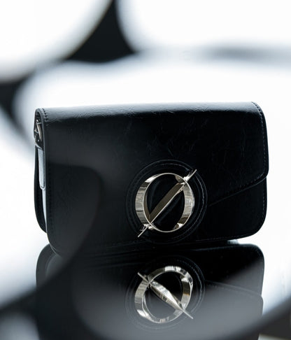 Black clutch bag with a logo on a reflective surface