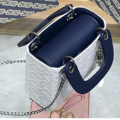 Side angle of GlowBags mini handbag showing embossed PU leather and navy handle
