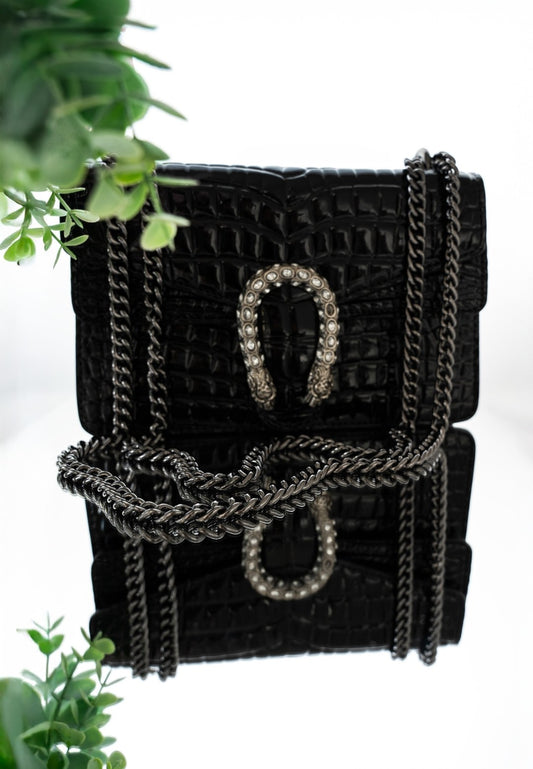 Black crocodile embossed shoulder bag with silver chain and horseshoe clasp – reflective surface display
