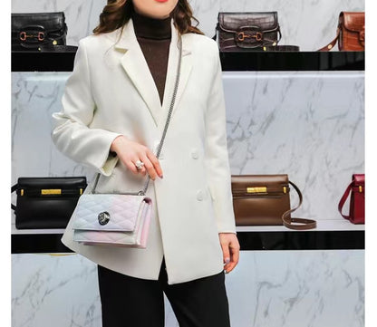Person wearing a white coat holding a handbag with a marble wall and bags in the background