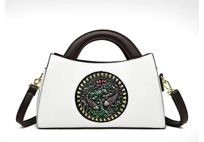White handbag with decorative circular emblem featuring birds on a white background