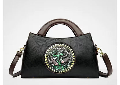 Black handbag with decorative emblem on a white background
