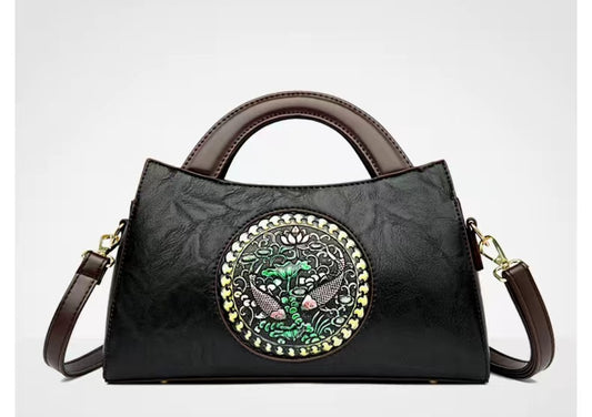 Black handbag with decorative emblem on a white background