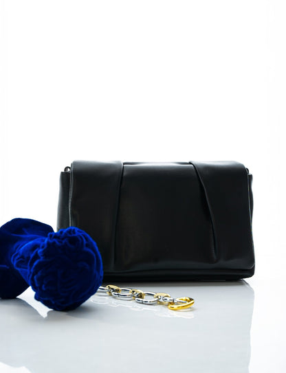 Black clutch bag with gold chain and blue flowers on a white background