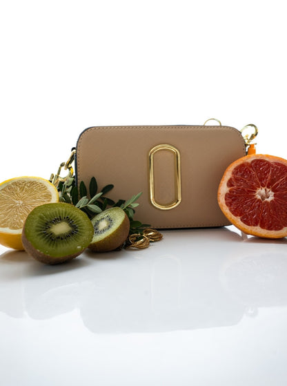 Beige handbag with gold accents surrounded by sliced fruits on a white background
