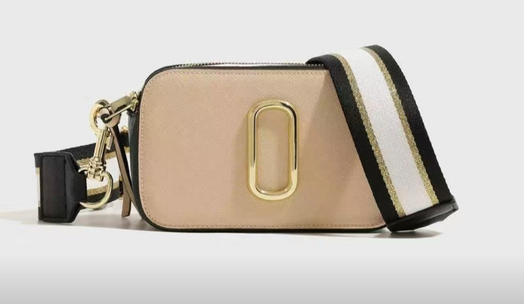 Beige handbag with gold clasp and black and white strap on a light gray background