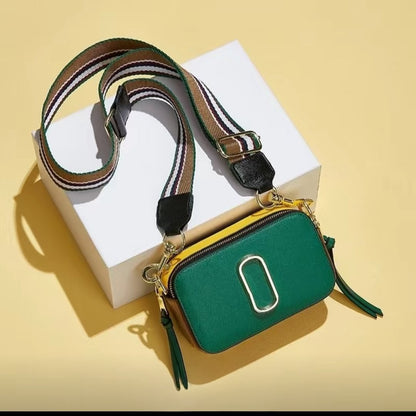 Green handbag with a striped strap on a yellow background
